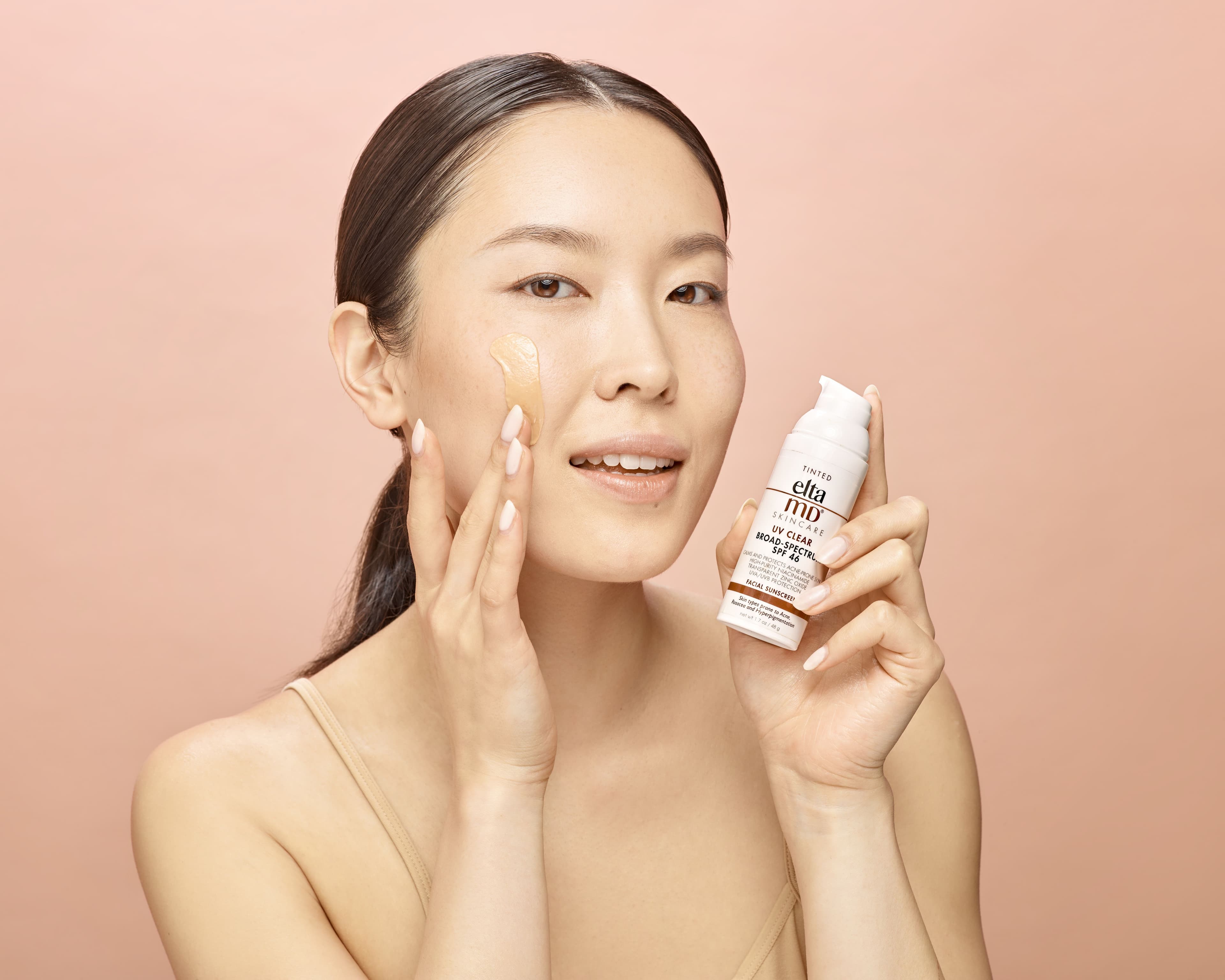 Holding a skincare product beside face